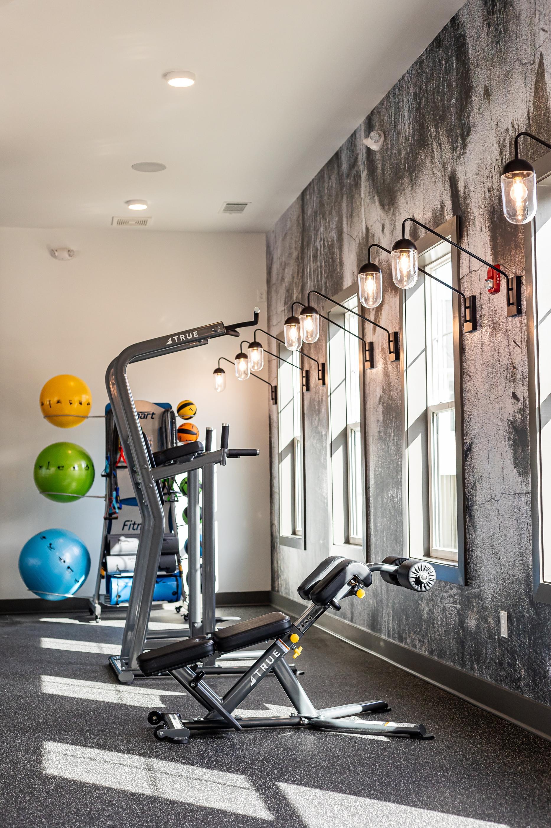 A gym with a weight machine and exercise balls.