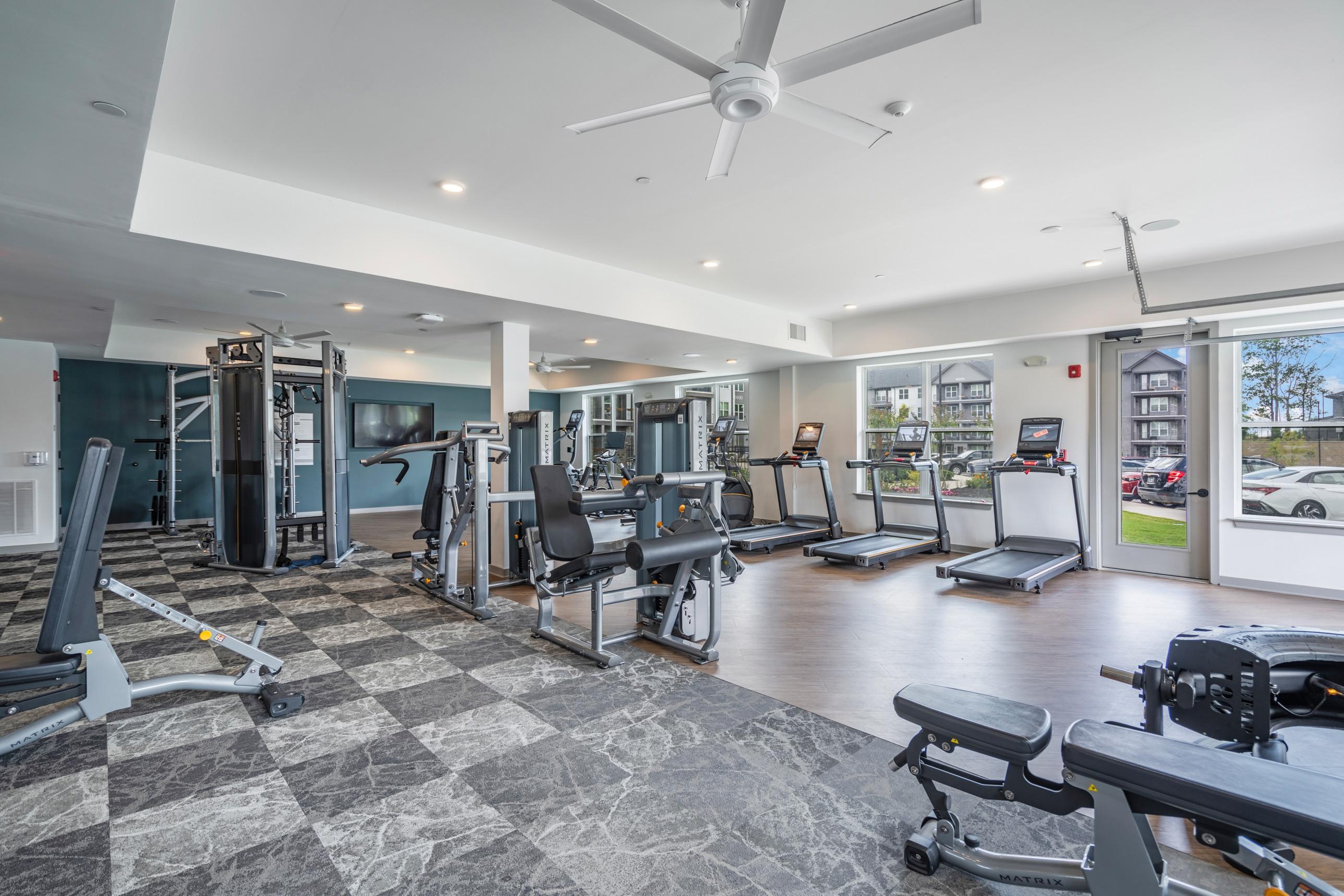 A spacious gym with a variety of equipment including treadmills, weights, and a bench press.