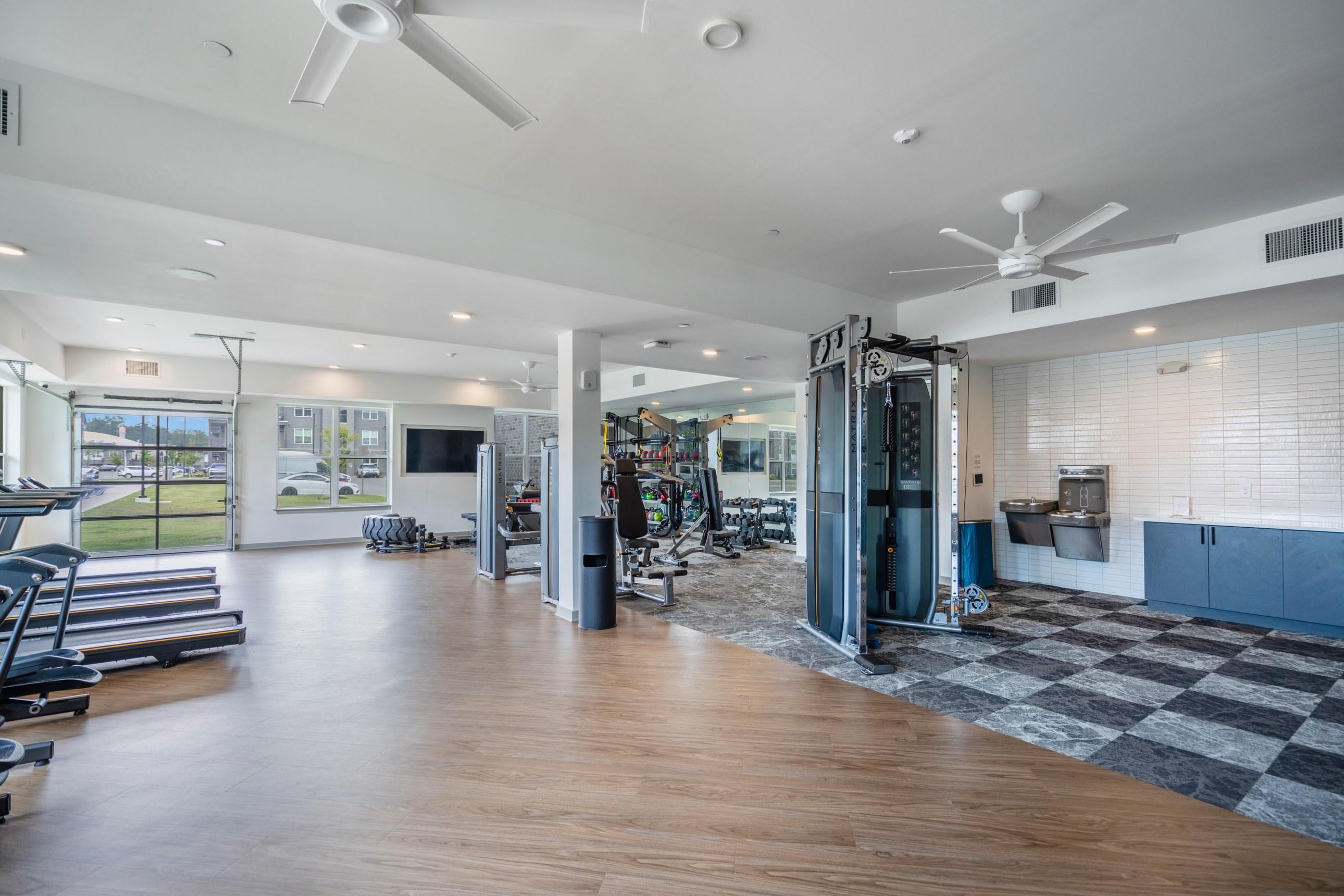 A spacious gym with wooden floors and various exercise equipment.