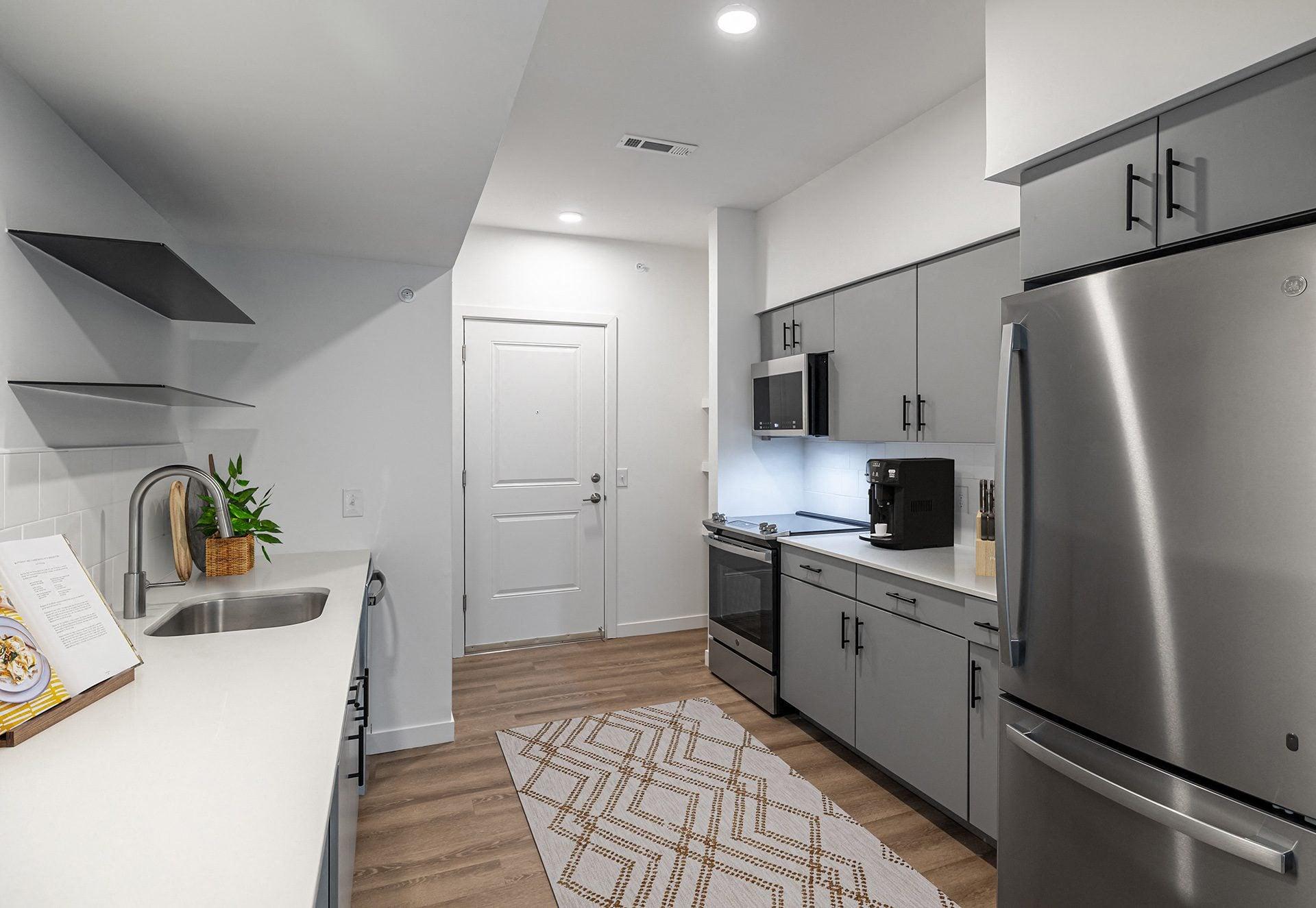 an open kitchen with stainless steel appliances and white countertops