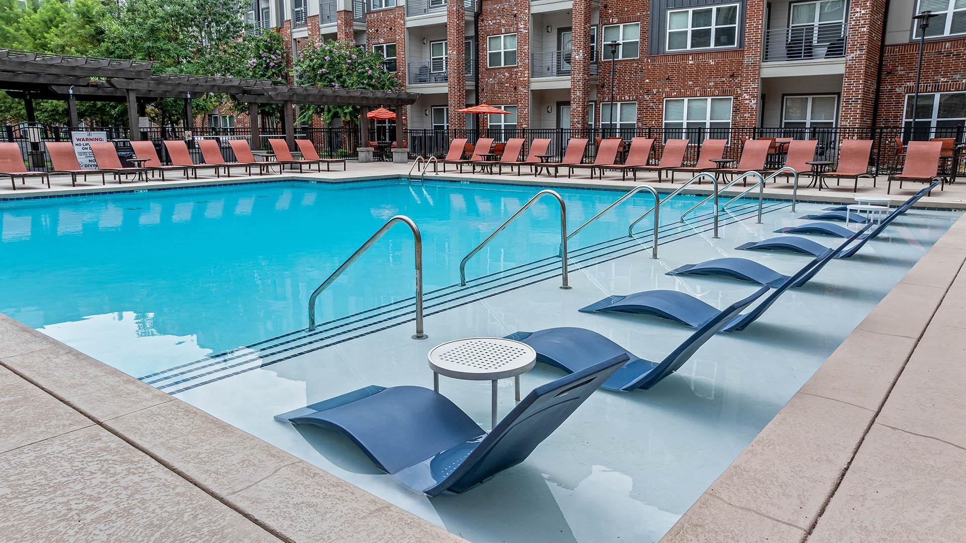 a swimming pool with chairs and a table in the middle