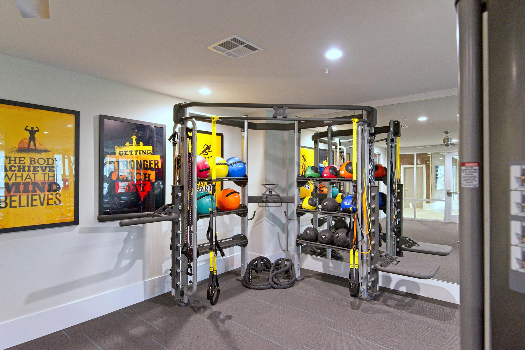 a fitness room with weights and a tv on the wall