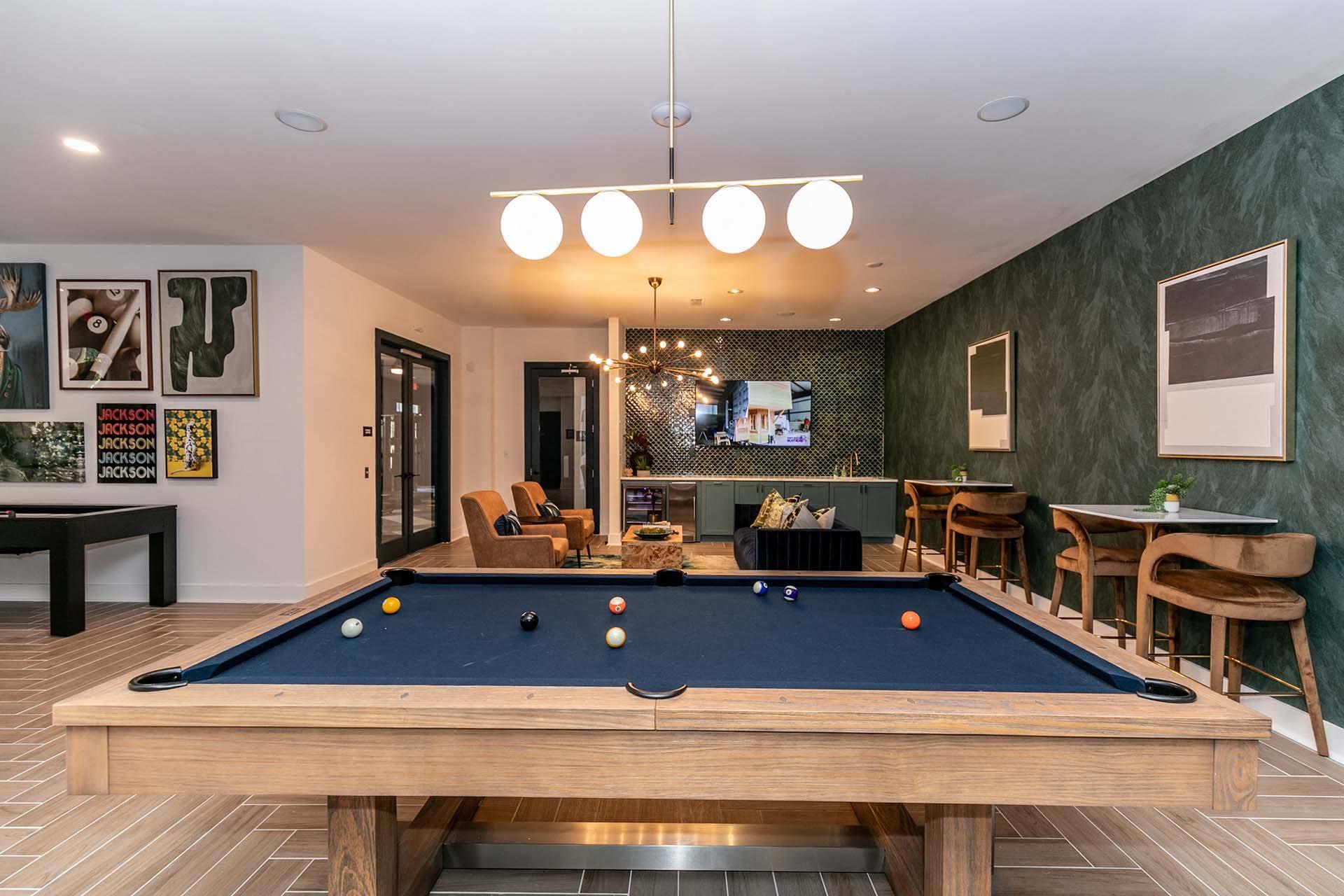 a pool table in a living room with a bar and a tv