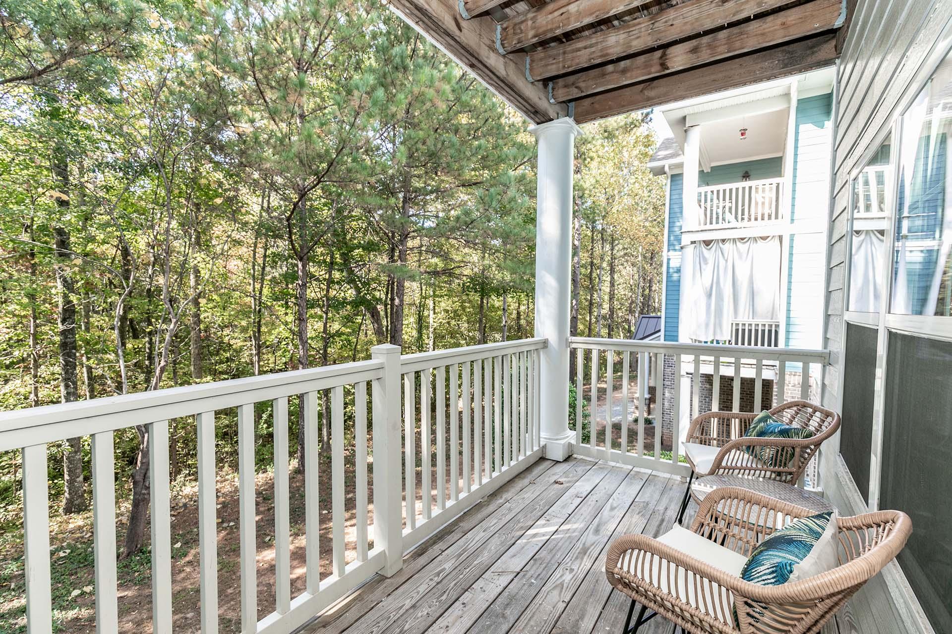 a porch with two wicker chairs and trees in the background