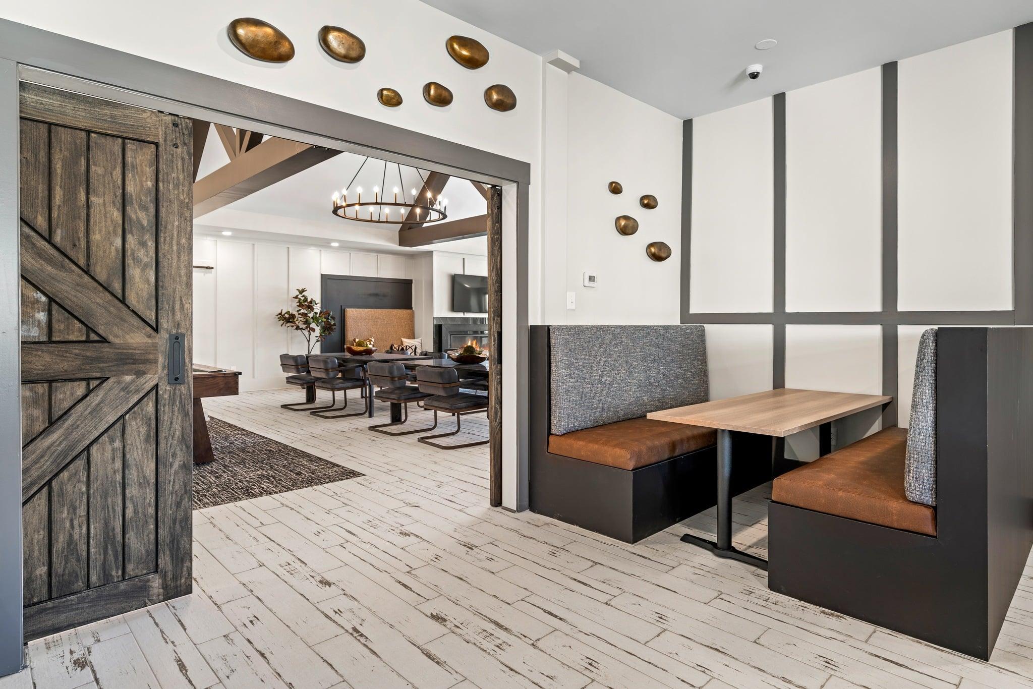 A modern dining room with a wooden floor and a large wooden door.