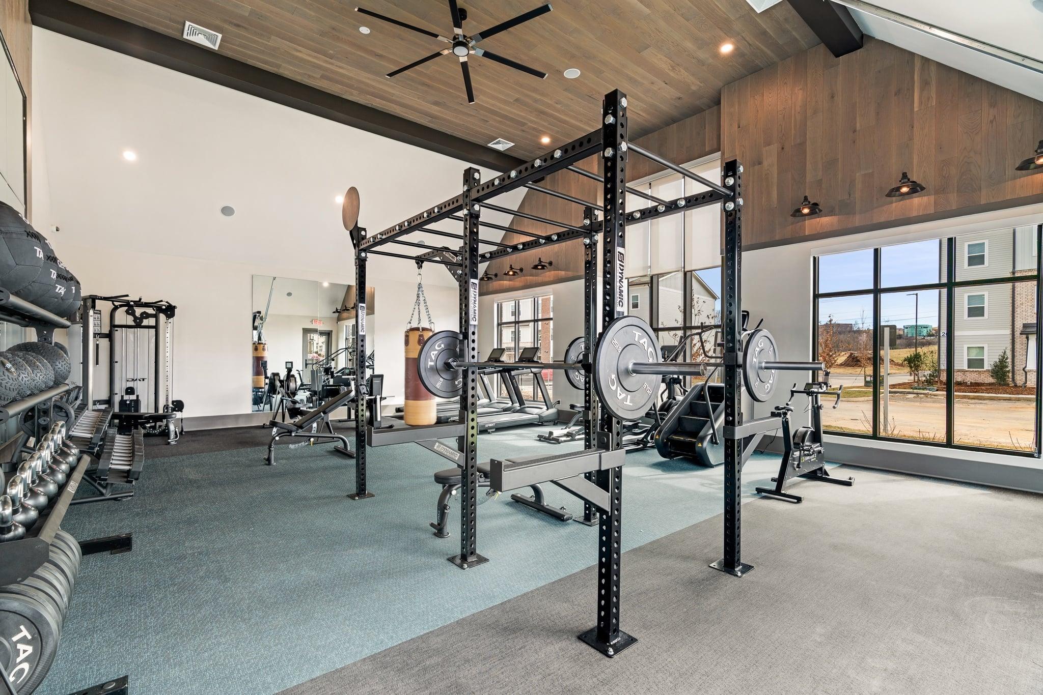 A spacious gym with a variety of equipment including a squat rack, bench press, and a barbell.