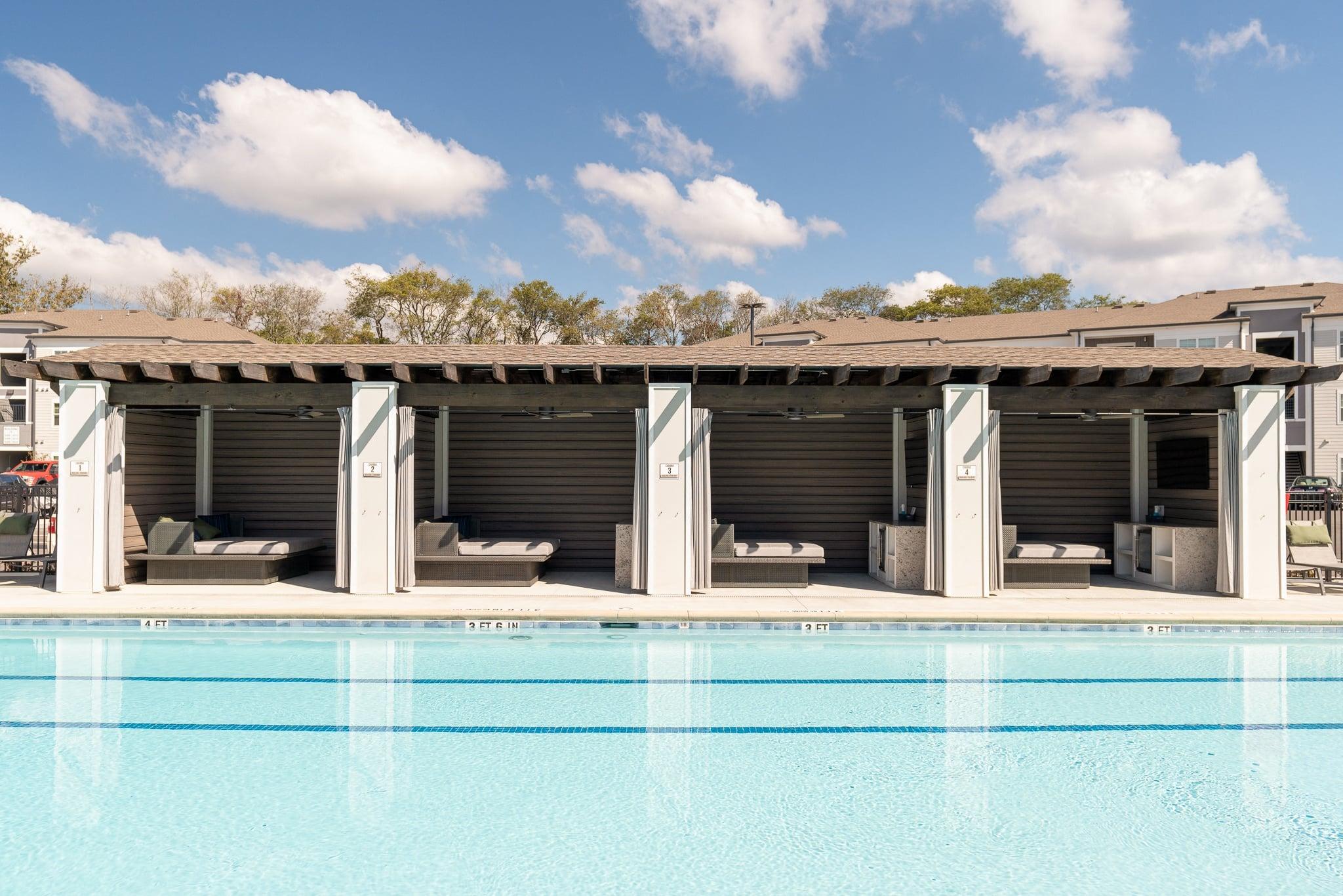a swimming pool with lounge chairs and a building with a roof