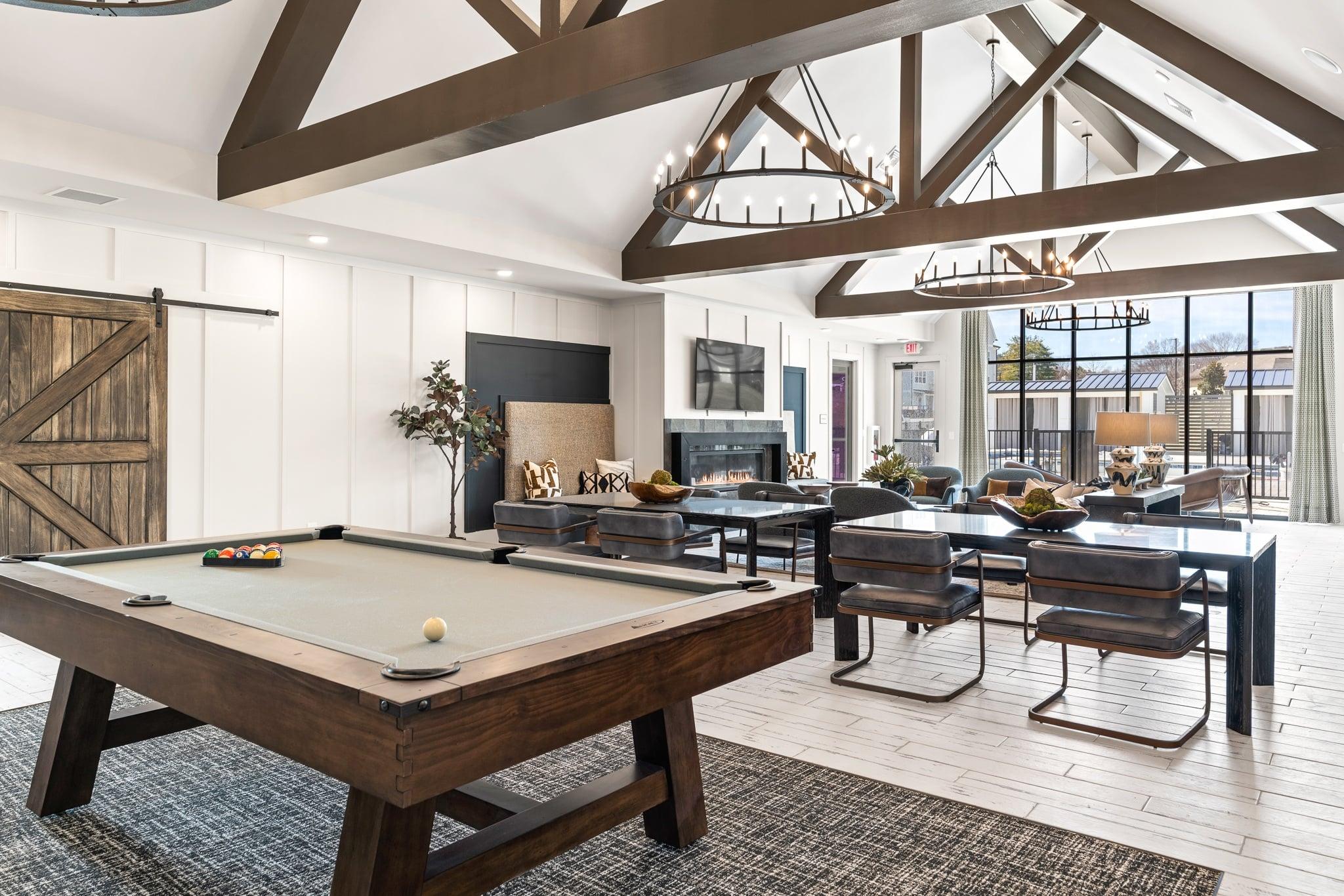 A pool table is in the middle of a room with a fireplace and a dining table.
