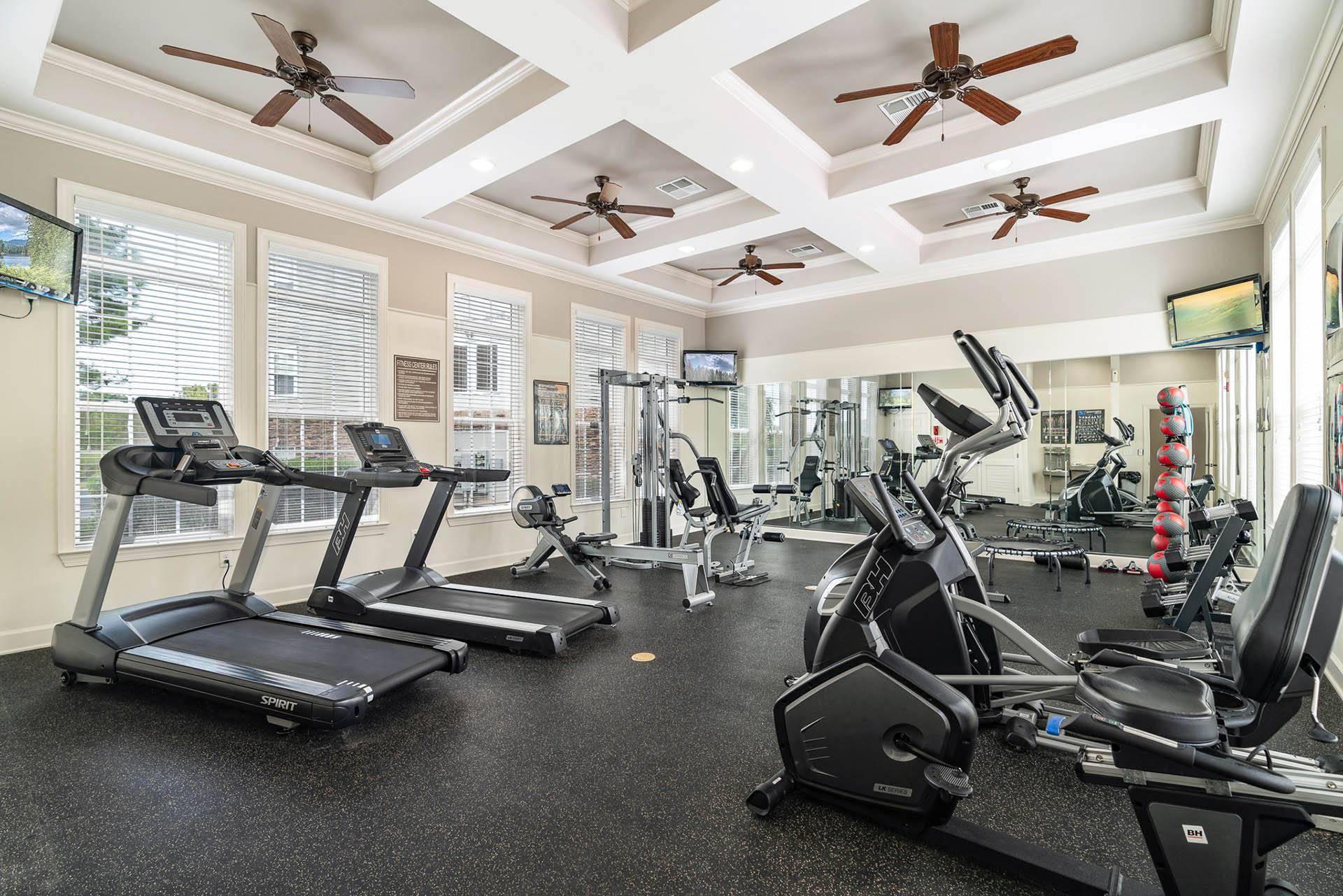 a gym with cardio machines and ceiling fans