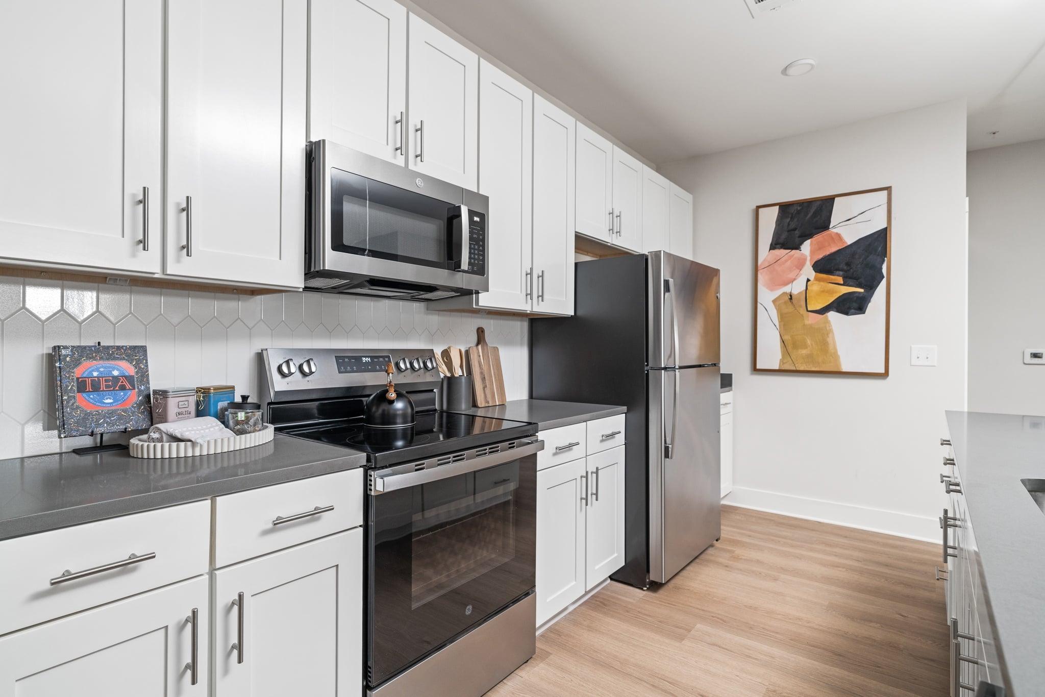 A modern kitchen with white cabinets and stainless steel appliances.