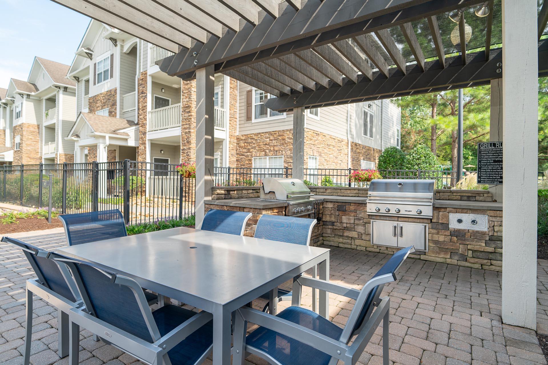 a patio with a table and chairs and a grill