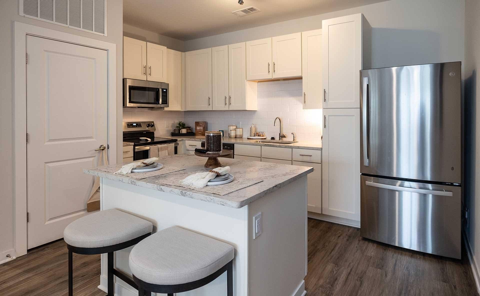 A kitchen with white cabinets and a marble countertop.