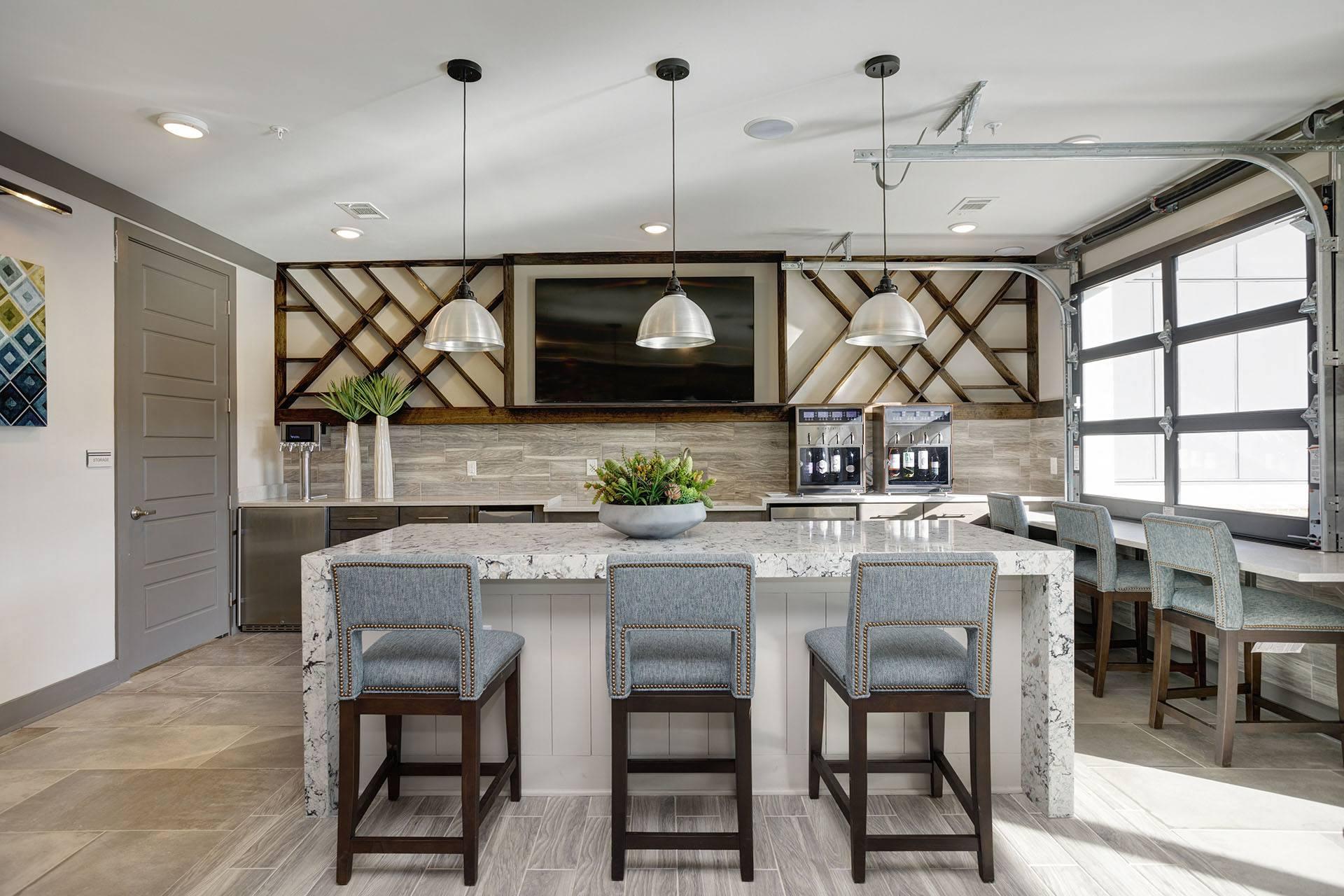 A kitchen with a marble island and bar stools.