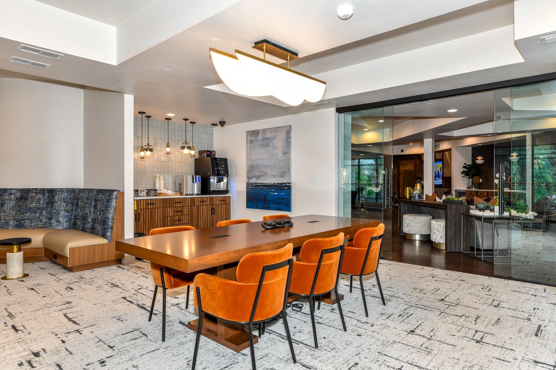 a dining area with a long wooden table and orange chairs