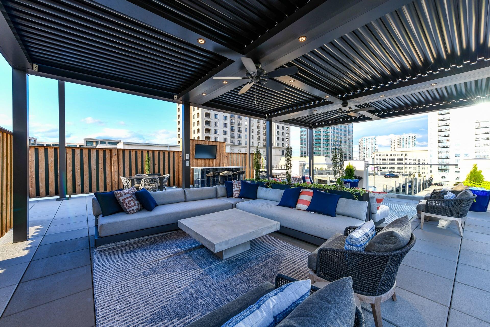 an outdoor living area with couches and chairs and a tv on the wall